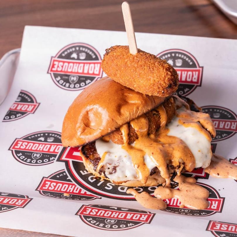 Woodside Roadhouse burger with melted cheese, special sauce, and a fried mozzarella stick on top.